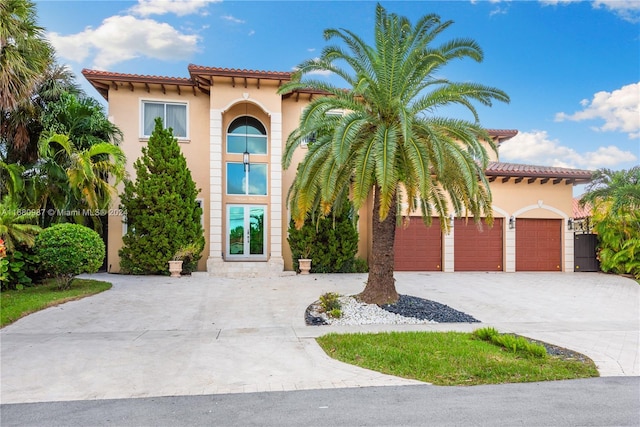 mediterranean / spanish house with a tiled roof, a garage, curved driveway, and stucco siding