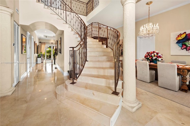 stairs with crown molding, a high ceiling, an inviting chandelier, and decorative columns