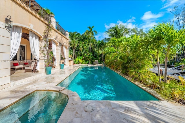 pool featuring a patio area, an outdoor hangout area, and an in ground hot tub