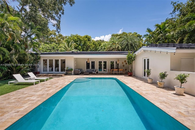 view of swimming pool with outdoor lounge area, a patio area, and french doors