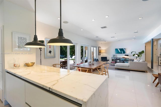 kitchen with light stone countertops, french doors, light tile patterned floors, decorative light fixtures, and white cabinetry