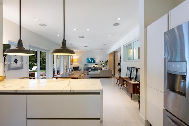 kitchen with pendant lighting, french doors, stainless steel fridge with ice dispenser, light stone counters, and white cabinetry