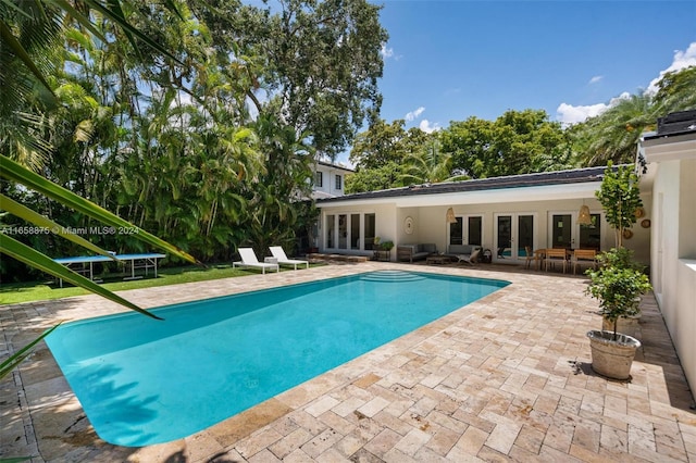 view of swimming pool with a trampoline, a patio, and french doors