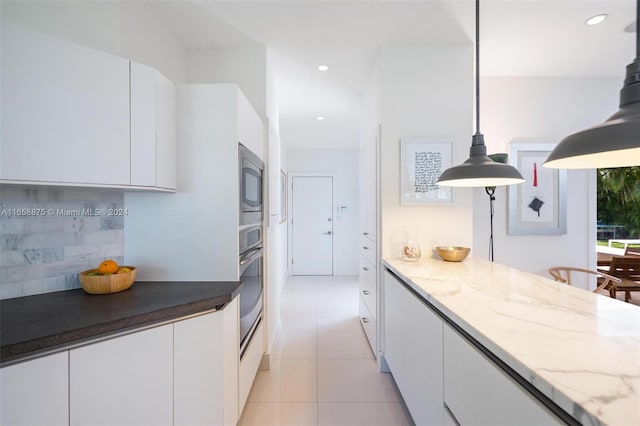 kitchen featuring tasteful backsplash, white cabinetry, hanging light fixtures, and dark stone countertops