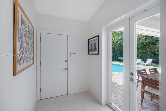 doorway to outside with lofted ceiling, light tile patterned floors, and french doors