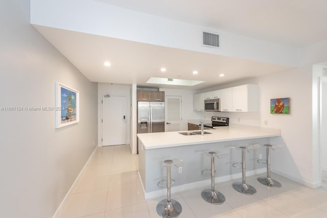 kitchen with sink, white cabinetry, kitchen peninsula, and stainless steel appliances