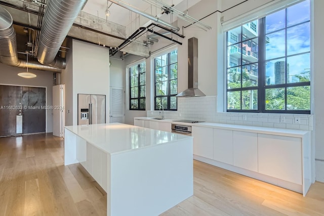 kitchen with a center island, a wealth of natural light, light hardwood / wood-style floors, white cabinetry, and extractor fan