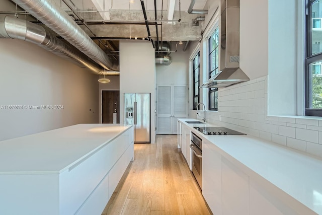 kitchen featuring white cabinets, wall chimney exhaust hood, a healthy amount of sunlight, and stainless steel appliances