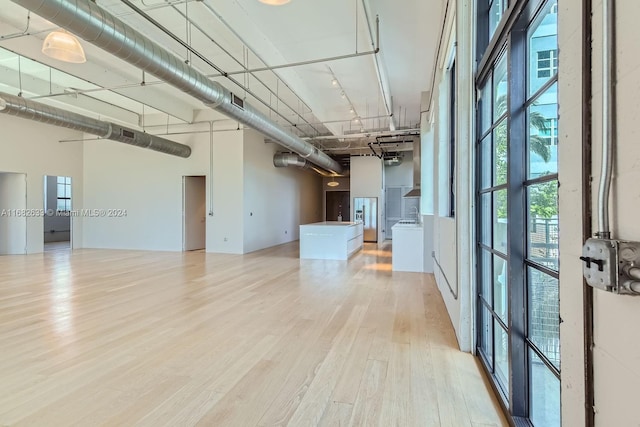 unfurnished room featuring light wood-type flooring and a high ceiling