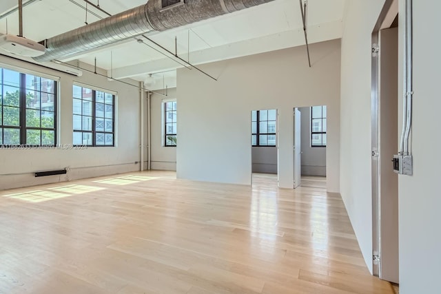 unfurnished room with a towering ceiling and light hardwood / wood-style flooring