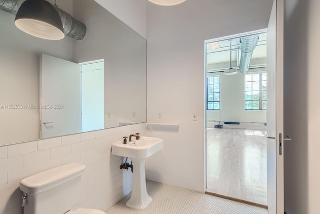 bathroom with tile patterned flooring, toilet, and tile walls