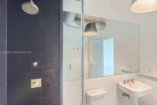 bathroom with sink, tile walls, and toilet