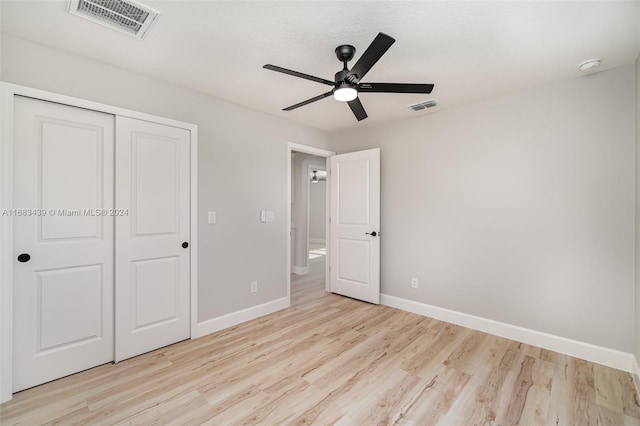 unfurnished bedroom with a closet, ceiling fan, a textured ceiling, and light hardwood / wood-style flooring