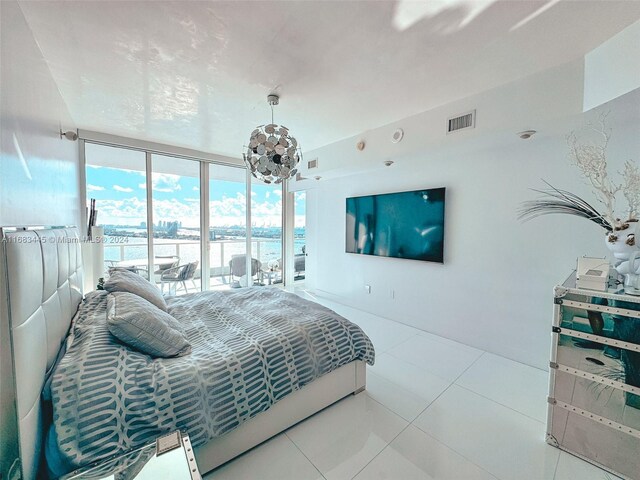 tiled bedroom with access to outside and a wall of windows