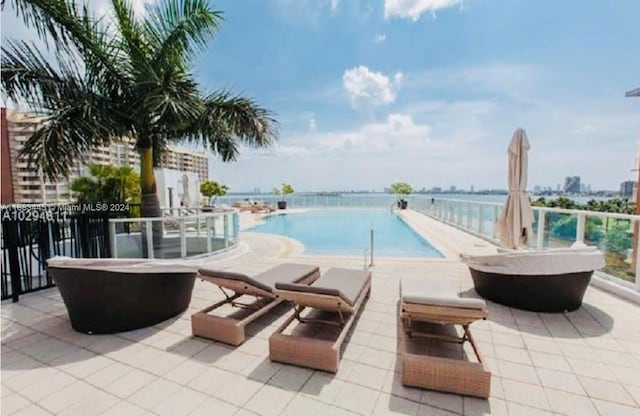 view of pool featuring a patio and a water view