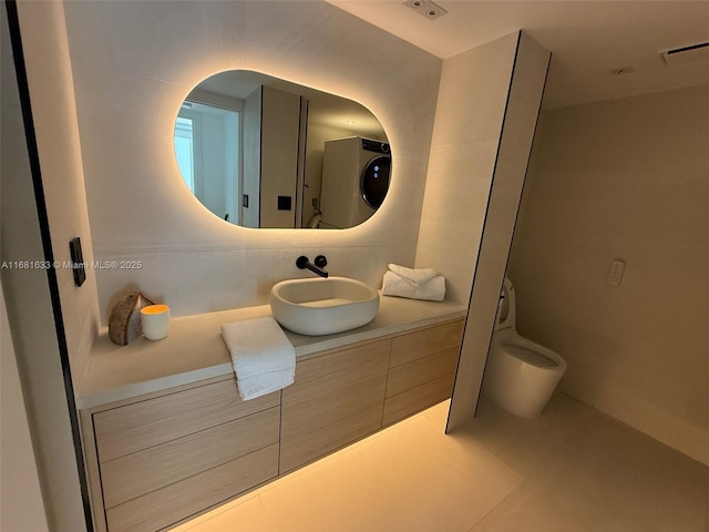 bathroom with washer / clothes dryer, vanity, and toilet