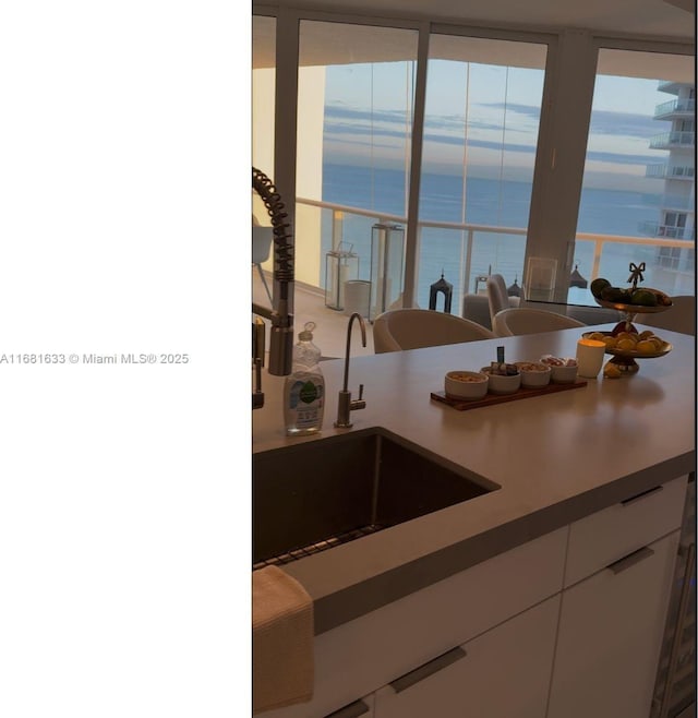 kitchen with white cabinets, a water view, sink, and a wealth of natural light