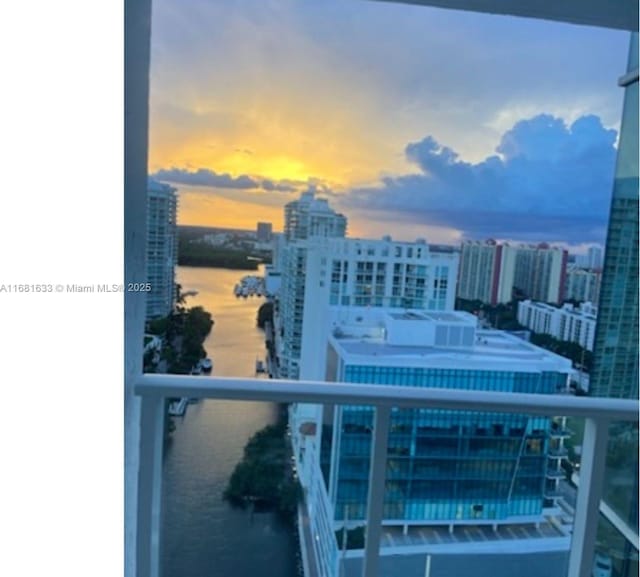 balcony at dusk featuring a water view