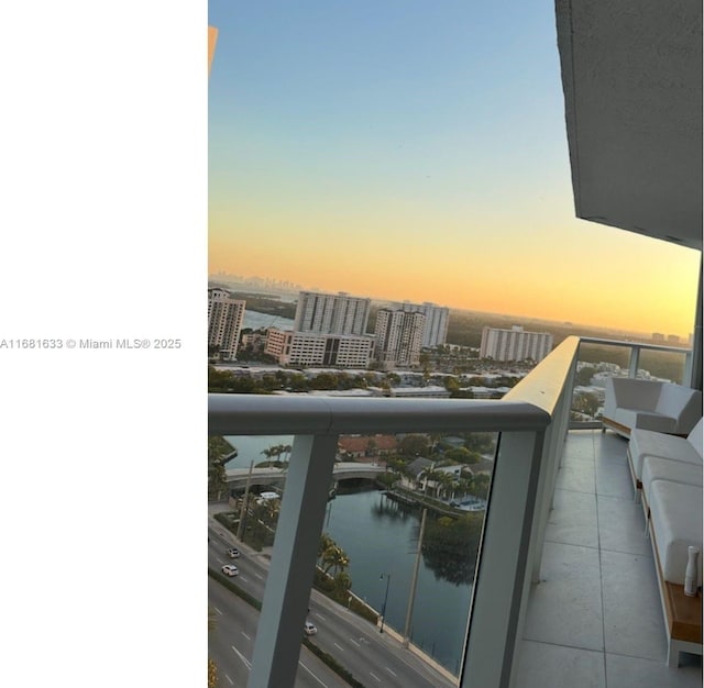 balcony at dusk featuring a water view