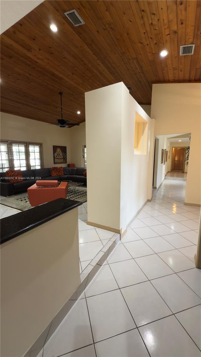 hallway with lofted ceiling, light tile patterned flooring, and wooden ceiling