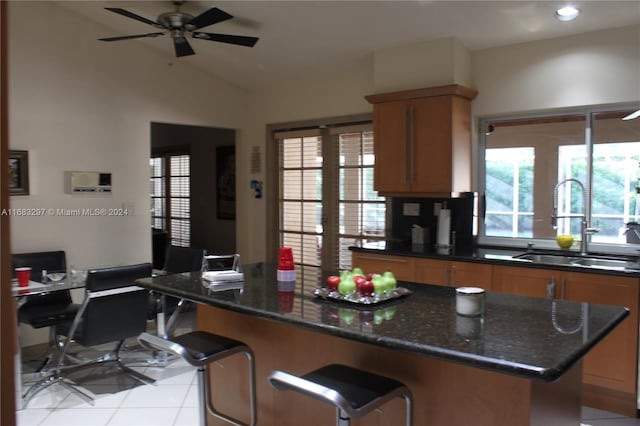 kitchen featuring sink, ceiling fan, vaulted ceiling, dark stone counters, and light tile patterned floors