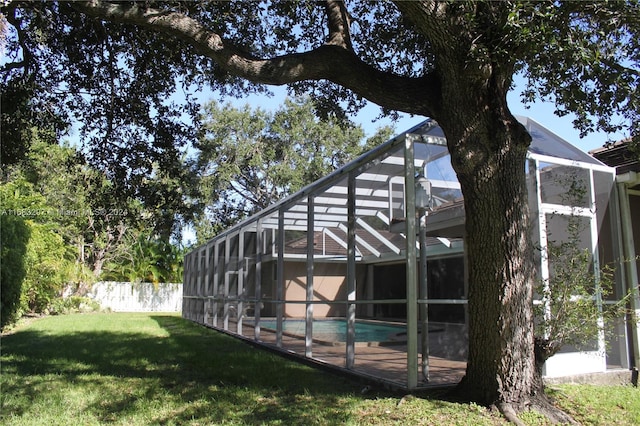 exterior space featuring a fenced in pool, glass enclosure, and a lawn