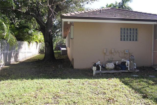 view of property exterior with central air condition unit and a lawn