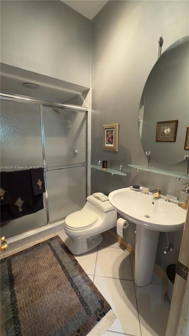 bathroom featuring toilet, a shower with shower door, and tile patterned floors