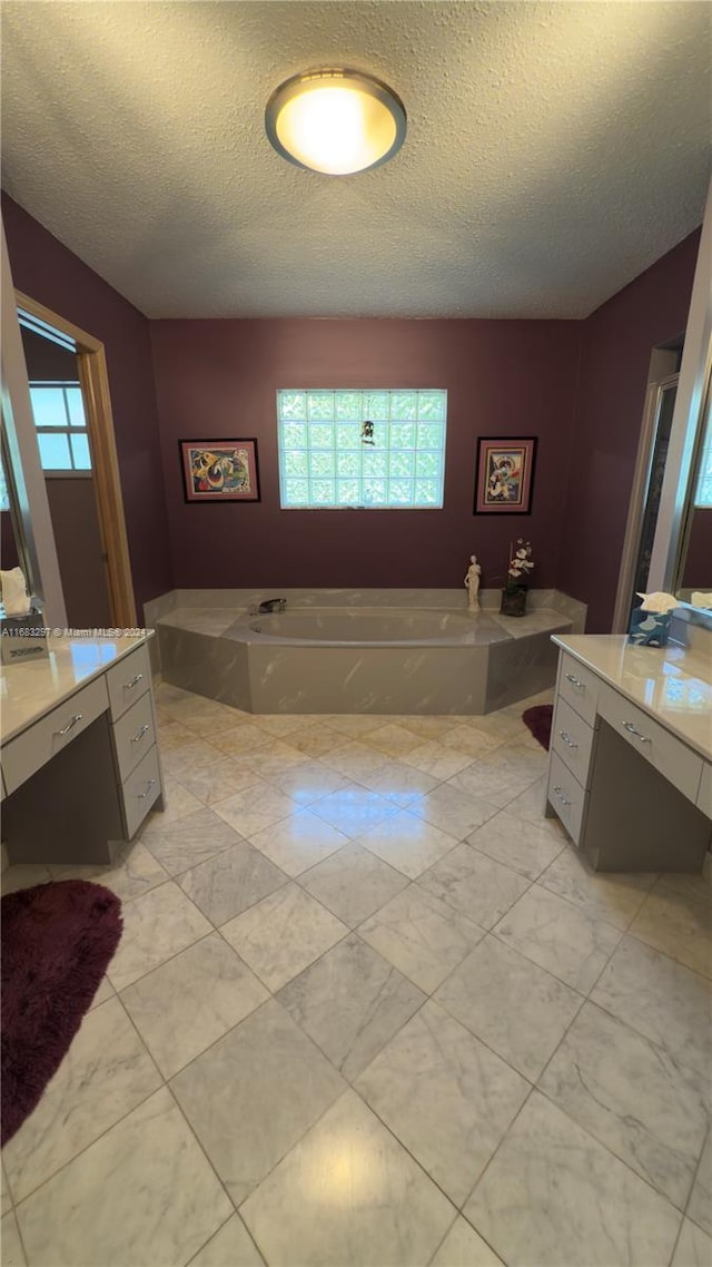 bathroom with vanity, a tub, a textured ceiling, and plenty of natural light