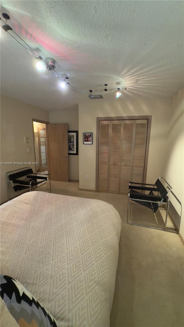 carpeted bedroom with a textured ceiling, a closet, and ceiling fan