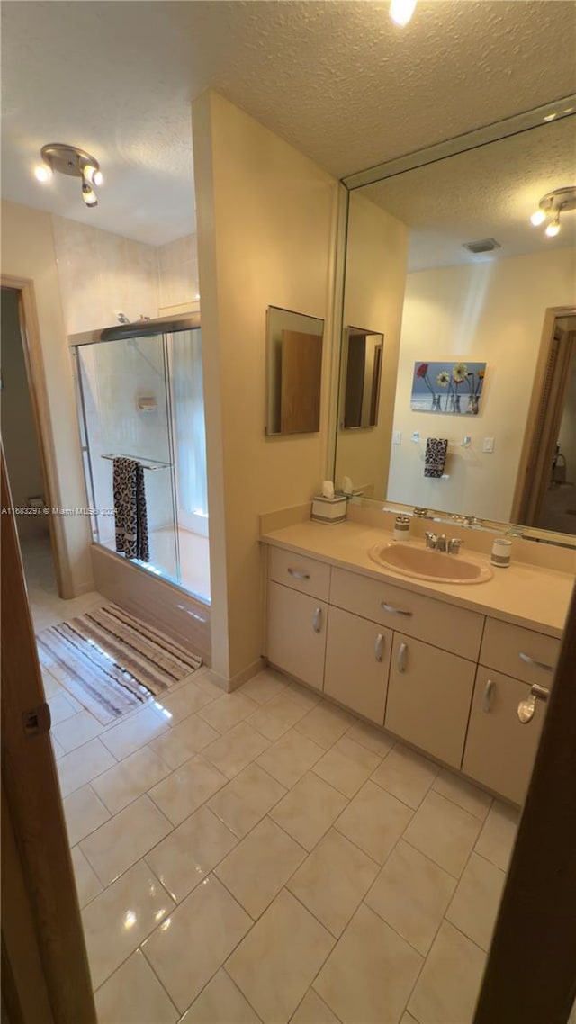 bathroom with vanity, a textured ceiling, a shower with shower door, and tile patterned floors