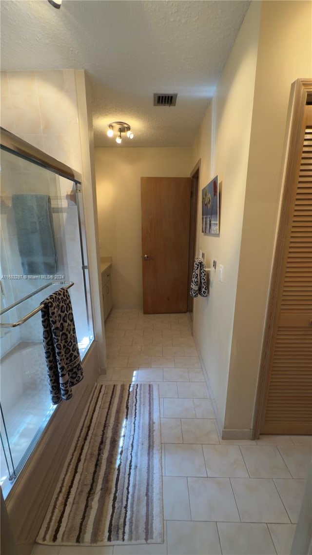 interior space with a shower with door, a textured ceiling, and tile patterned flooring