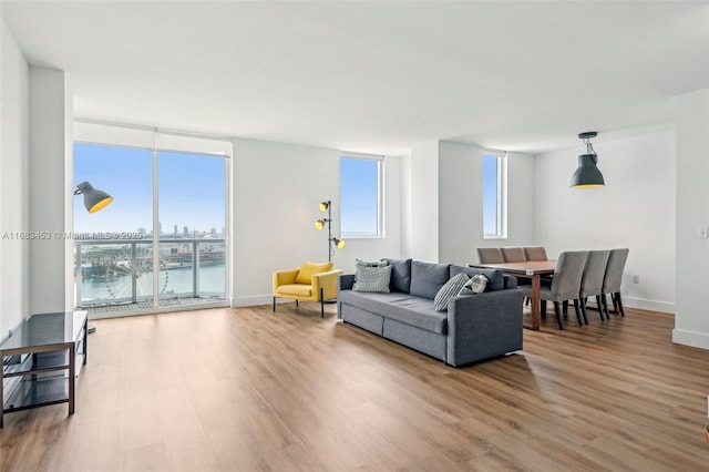 living room featuring hardwood / wood-style flooring, a water view, and a wall of windows