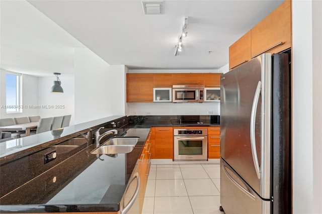 kitchen with track lighting, decorative light fixtures, stainless steel appliances, sink, and light tile patterned floors