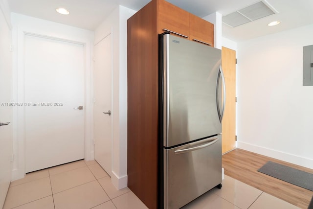 kitchen featuring electric panel, light tile patterned floors, and stainless steel fridge