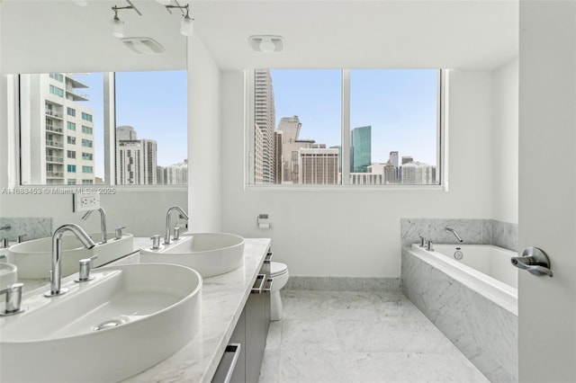 bathroom with tile patterned floors, tiled bath, a wealth of natural light, and vanity