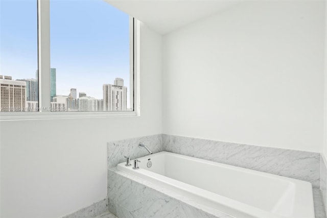 bathroom featuring tiled bath and a wealth of natural light