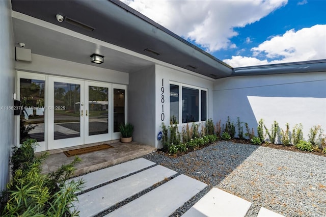 view of exterior entry featuring stucco siding, a patio, and french doors