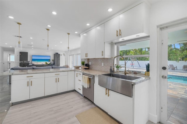 kitchen featuring sink, stainless steel dishwasher, white cabinets, and kitchen peninsula