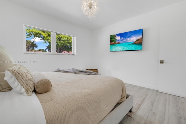 bedroom with a notable chandelier, baseboards, and wood finished floors