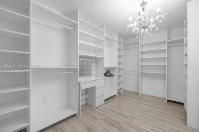 walk in closet featuring a chandelier and light wood-style flooring