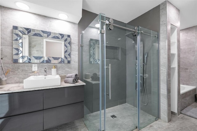 bathroom featuring a stall shower, tile walls, and vanity