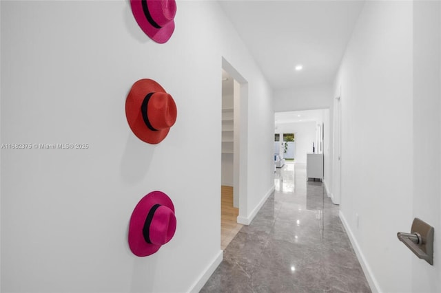 corridor with marble finish floor and baseboards