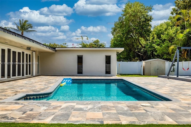 view of swimming pool with a fenced in pool, a patio, an outbuilding, fence, and a shed