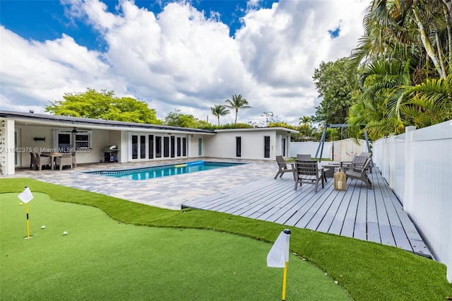 view of swimming pool featuring a deck, a fenced backyard, a grill, a ceiling fan, and a fenced in pool