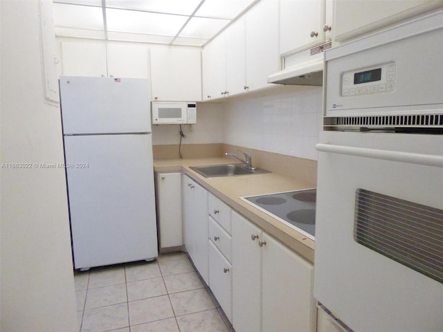 kitchen featuring decorative backsplash, sink, light tile patterned flooring, white cabinets, and white appliances