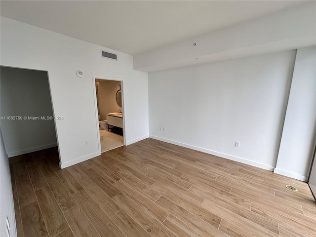 unfurnished bedroom with ensuite bath and light hardwood / wood-style floors