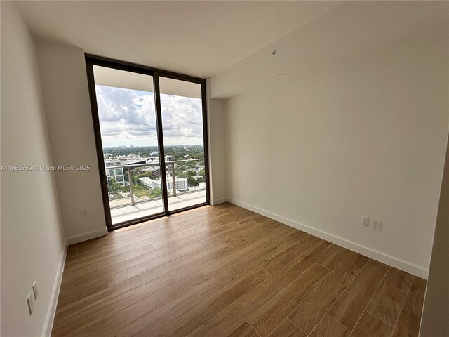 unfurnished room with expansive windows and light hardwood / wood-style flooring