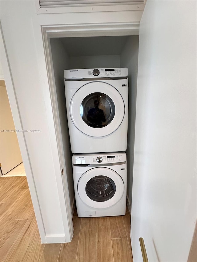 laundry room with stacked washer / drying machine and light hardwood / wood-style floors