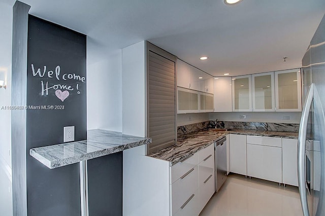 kitchen featuring appliances with stainless steel finishes, stone countertops, kitchen peninsula, white cabinets, and light tile patterned floors